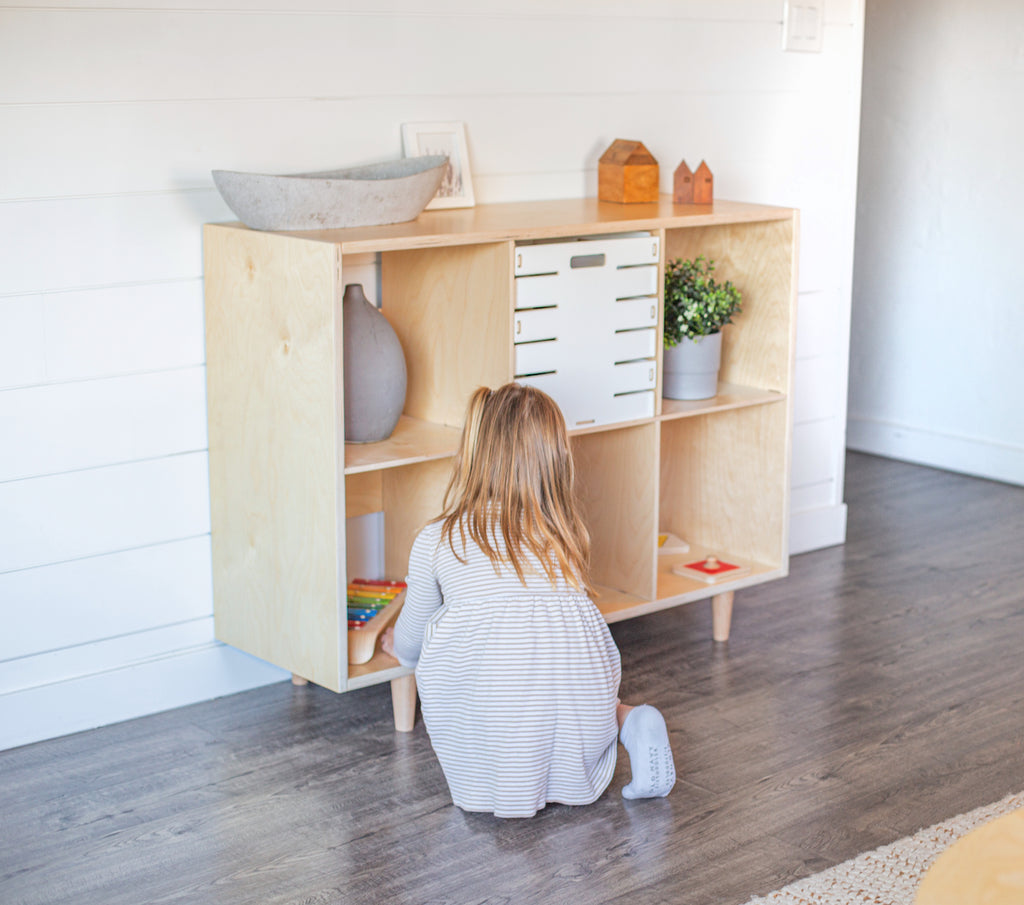 six cube shelf in a living room with a young child